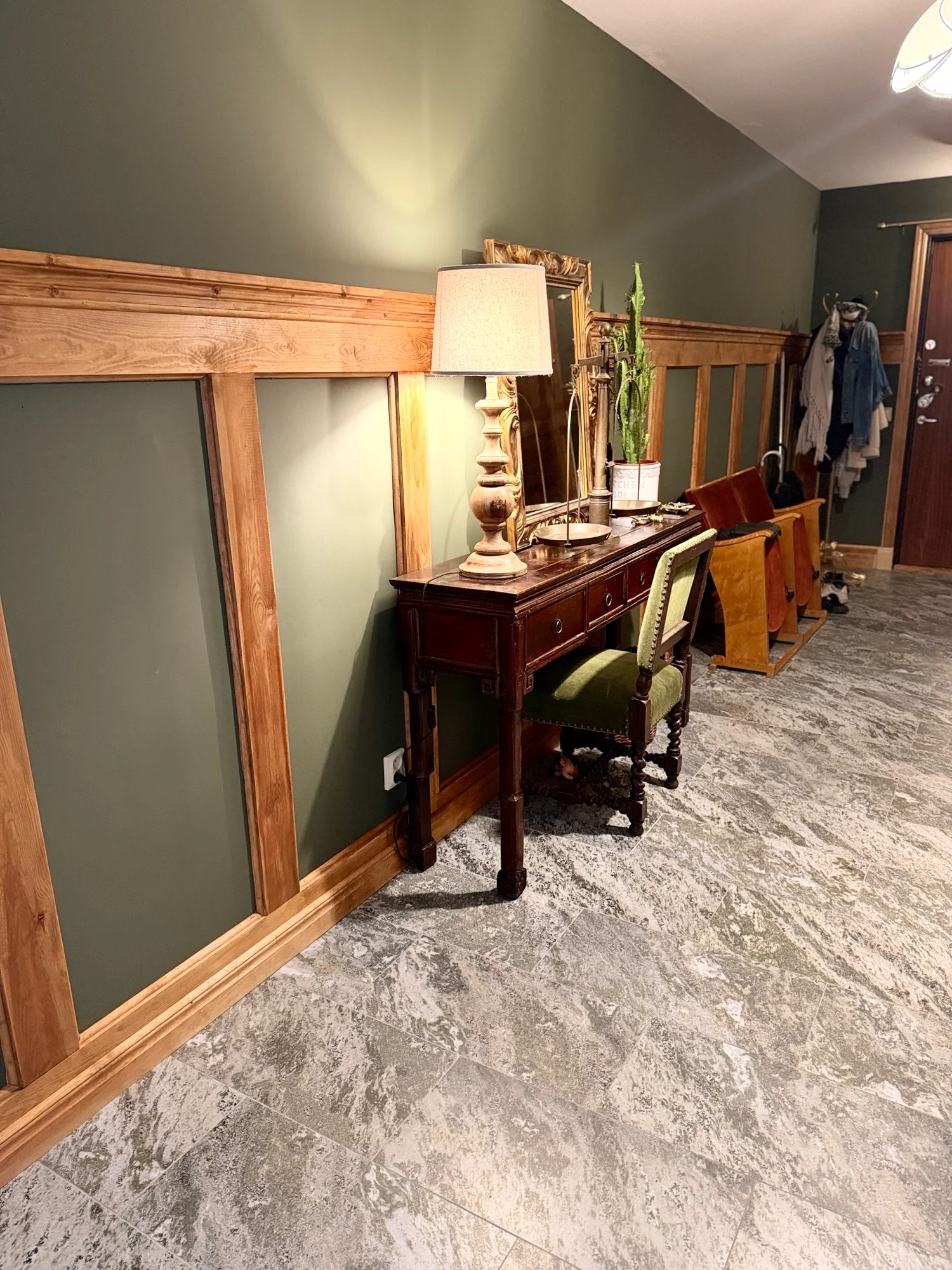 Hall med olivoljegrön vägg, träpanel och marmorliknande golv